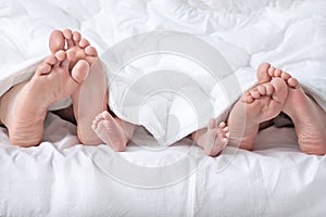 Funny family feet under the white blanket