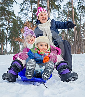 Funny family is sledging in winter-landscape