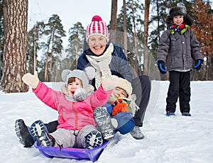 Funny family is sledging in winter-landscape