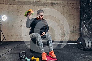 Funny fat girl with burger is surprises at her kilograms