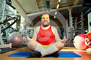 Funny fat man with a beard doing yoga in the gym