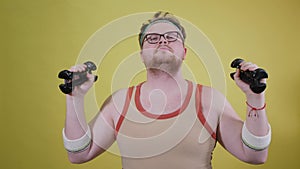 Funny fat man doing exercises with dumbbells. Overweight. yellow background