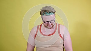 funny fat man doing exercises with dumbbells. Overweight. yellow background