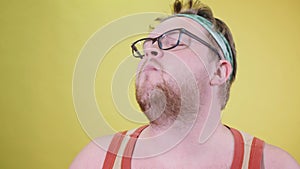 funny fat man doing exercises with dumbbells. Overweight. yellow background