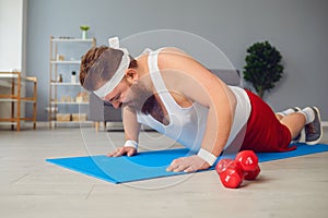 Funny fat man doing exercises on the floor smiling on the floor at home.