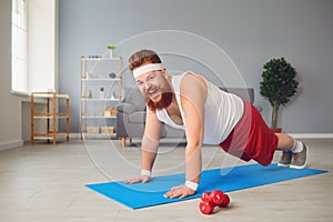 Funny fat man doing exercises on the floor smiling on the floor at home.