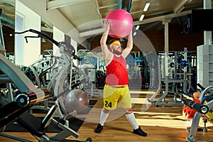 A funny fat man doing exercises in the gym.