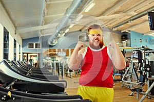 A funny fat man doing exercises in the gym.