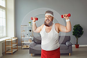 Funny fat man with dumbbells doing exercises in the room.