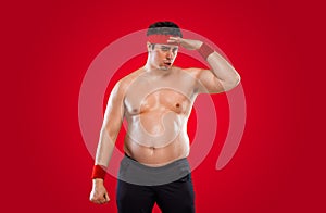 A funny fat man isolated on red background. Obesity and eating disorder. Concept for dietetics and fitness advertising