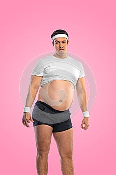 A funny fat man  on pink background. Obesity and eating disorder. Concept for dietetics and fitness advertising