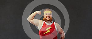Funny fat man in sports clothes shows a hand with muscles biceps