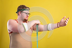 Funny fat man in sportswear measures the volume of his arm