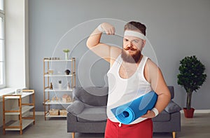 Funny fat man in sportswear shows muscles standing in the room at home