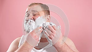 Funny fat middle-aged man in t-shirt while applying facial shaving foam, slow motion