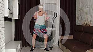 Funny fat sportsman man athlete in sportswear making sport fitness exercise with dumbbells at home