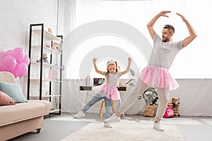 funny father and daughter in pink tutu skirts dancing