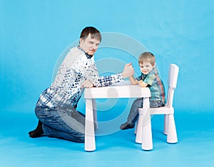 Funny father and little son competing in arm wrestling