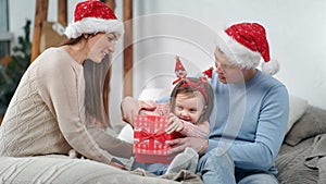 Funny female baby opening present get out gold shining ball surrounded by lovely mother and father