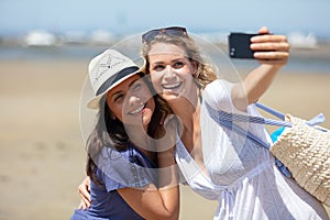 funny female friends on vacation taking selfies on beach