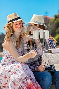 Funny female friends on vacation taking selfies on the beach with a smart phone