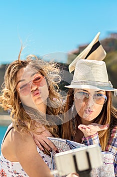 Funny female friends on vacation taking selfies on the beach with a smart phone