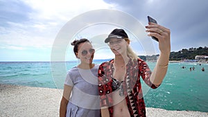 Funny female friends on vacation taking selfies on the pier with a smart phone