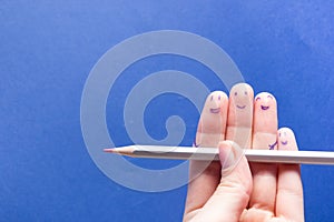 Funny fingers holding pencil and smiling. Friendship teamwork concept on blue background with copy space for ad text.