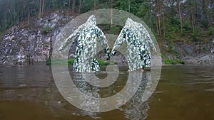 Funny flex in camouflage raincoats. Two teenagers perform synchronized dance moves in the rain, standing knee-deep in