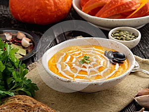 Funny food for Halloween. Pumpkin puree soup, spider web, dark old wooden table, side view.