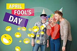 Funny friends with megaphone on color background. April Fools' Day prank