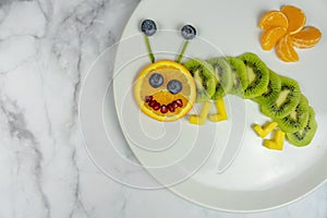 Funny fruit worm on white plate healthy dessert for kids