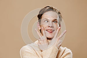 funny, funny guy in a beige sweater makes a funny face sticking out his tongue