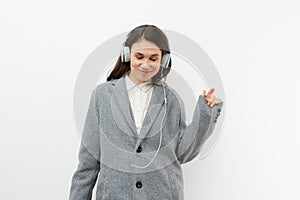 a funny, funny, sweet woman stands on a light background listening to music in her headphones and dancing with her hands