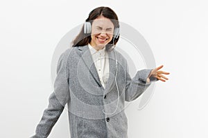 a funny, funny, sweet woman stands on a light background listening to music in her headphones and dancing with her hands