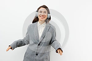 a funny, funny, sweet woman stands on a light background listening to music in her headphones and dancing with her hands