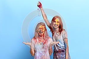 Funny ginger girl throwing colored powder on her friend`s head