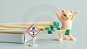 Funny ginger toy kitten with raised paws next to open matchbox and Danger warning sign. Concept of teaching children fire safety