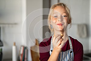 Funny girl in apron eating handmade cookie