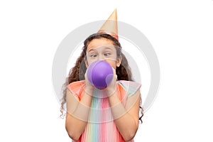 funny girl in birthday party hat blowing balloon