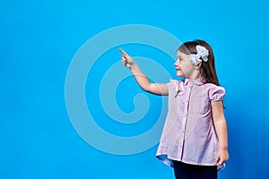 funny girl on a blue background points her finger to the side