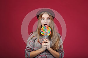 Funny girl eating big striped lollipop