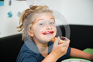 Funny girl eating bread roll with marmelade