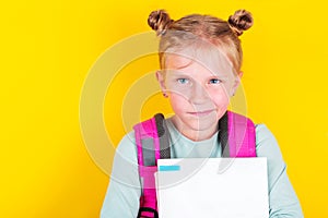 Funny girl from elementary school with book and backpack on yellow background. School concept,education. Back to School.