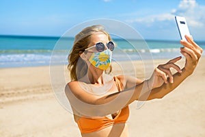Funny girl in face mask taking selfie photo on beach