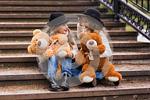 Funny girl girlfriend sitting on the stairs with soft toys in the park.