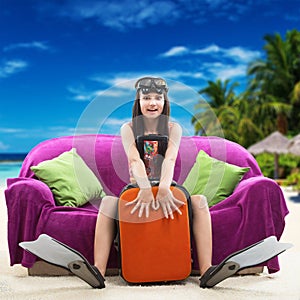 Funny girl with her luggage, tropical beach background