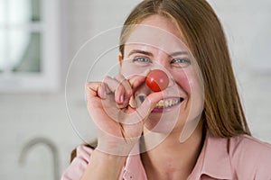 Funny girl holds a cherry tomato near her nose