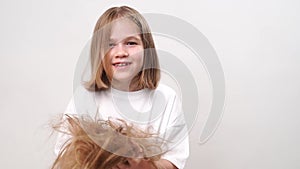 funny girl holds in hands cropped hair after cutting and throws them up on white