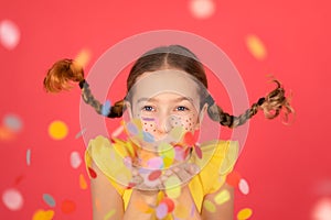 Funny girl playing at home. Child blowing confetti